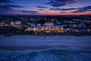 Un hôtel situé en bord de mer, composé de plusieurs bâtiments, avec une plage de sable et des vagues de l’océan.