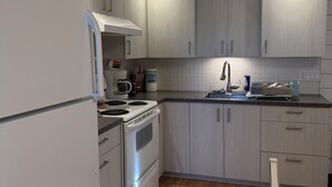 Une cuisine moderne avec des meubles de couleur bois clair, un réfrigérateur en acier inoxydable, un four encastré et une table à manger en bois.