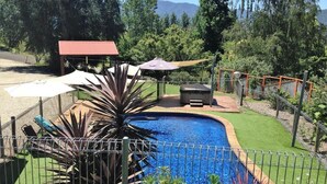 A swimming pool with a surrounding fence, a barbecue area, and a covered seating area. - Snowview Holiday Units (Tawonga South)