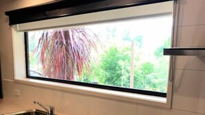 A kitchen with a window, stainless steel sink, and a dishwasher. - Snowview Holiday Units (Tawonga South)