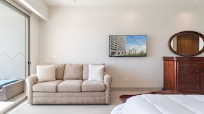 Ein modernes Schlafzimmer mit einem beigefarbenen Sofa, einem großen Bett, einer Holzkommode und einem Stadtbild an der Wand.