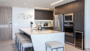 Una cocina moderna con una isla de mármol, electrodomésticos de acero inoxidable y una zona de bar con asientos.