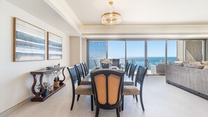 Un comedor amplio con vista al océano, un candelabro y un ventanal grande.