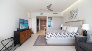 Ein modernes Hotelzimmer mit Bett, Nachttischlampen, Fernseher, Kommode und Meerblick.
