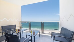 Ein Balkon mit Meerblick, ausgestattet mit Tischen und Stühlen sowie einer Glasabtrennung.