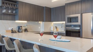 Una cocina moderna con encimera de mármol, electrodomésticos integrados y una copa de vino.