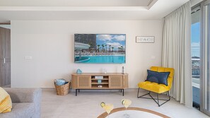 Ein modernes Wohnzimmer mit Blick auf einen Pool, ein gelber Sessel und ein gerahmtes Bild von einer Strandansicht.