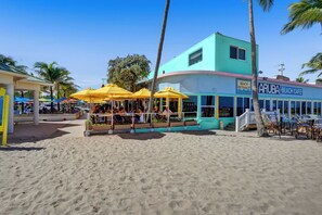 A beachside cafe with outdoor seating and palm trees. - Pet Friendly Lauderdale by The Sea Beach Pad! (Lauderdale-by-the-Sea)