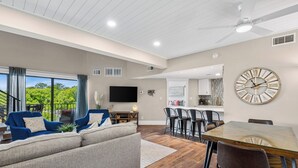 A modern living room with a sofa, a dining table, and a kitchen area.