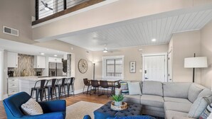 A spacious living area with a kitchen, dining area, and a large gray sofa.