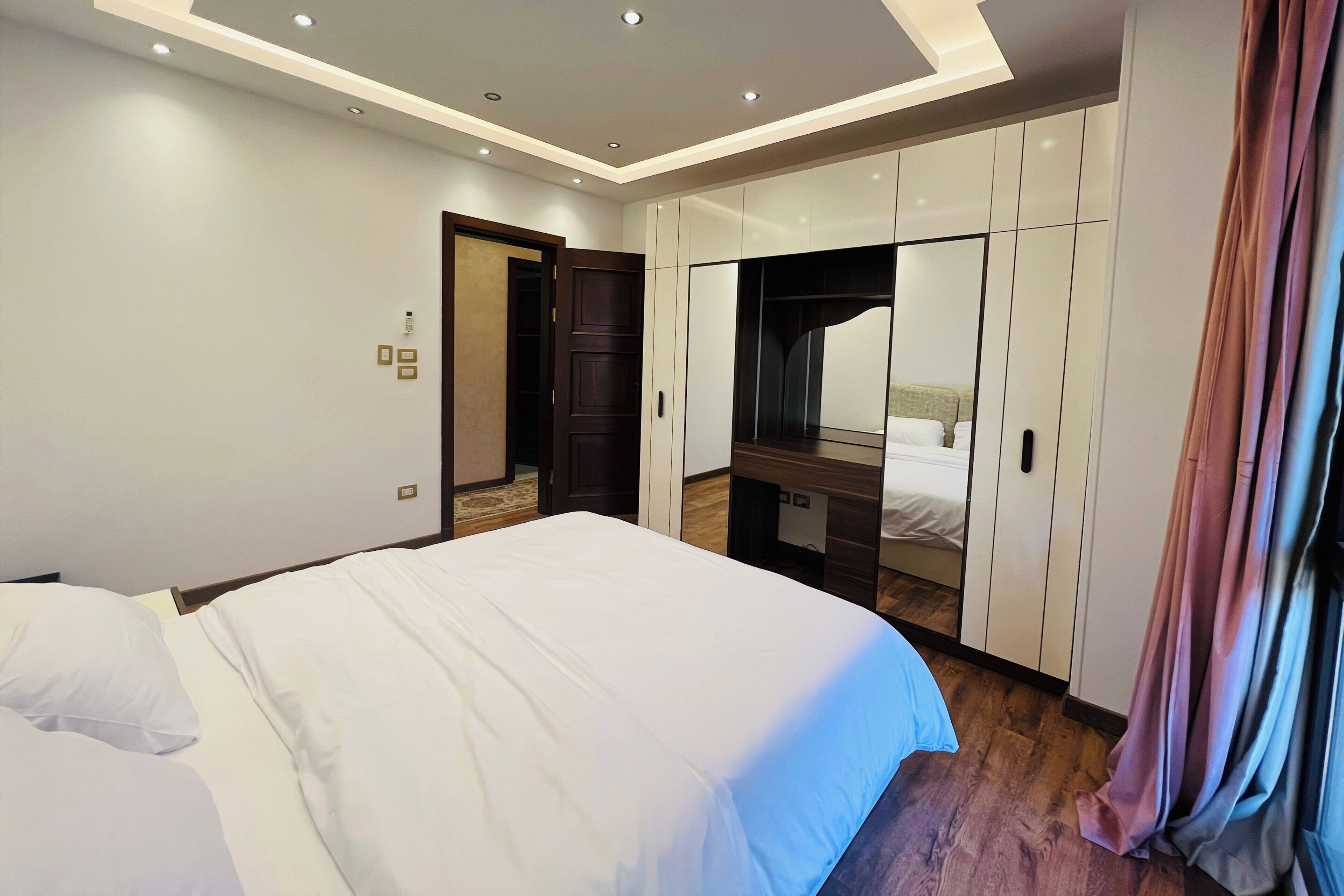 Een moderne slaapkamer met een groot bed, een inbouwkast en een spiegel.
