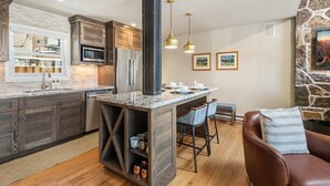 Una cocina moderna con una isla central, armarios de madera y una pared de acento de piedra.