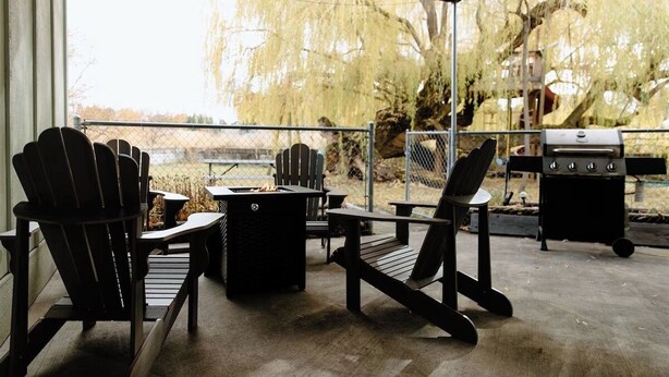 An outdoor patio with Adirondack chairs, a fire pit, and a grill. - Willow South Cottage (Moscow)