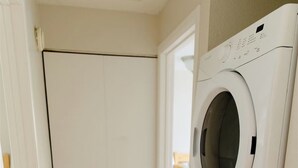A laundry room with two stacked front-loading washing machines and a wooden floor. - Willow South Cottage (Moscow)