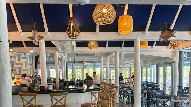 A spacious bar area with wooden flooring, wicker bar stools, and hanging pendant lights. - Beautiful Updates - Relaxing Views - Close to Pool (Naples)