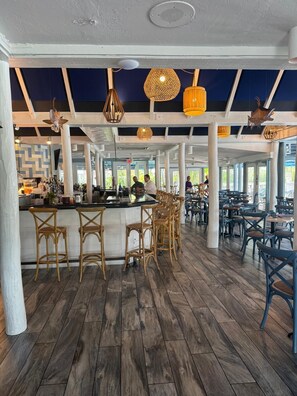 A spacious bar area with wooden flooring, wicker bar stools, and hanging pendant lights. - Beautiful Updates - Relaxing Views - Close to Pool (Naples)