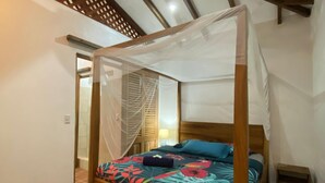 Een slaapkamer met een hemelbed van hout, een baldakijn en een bloemenbeddengoed.