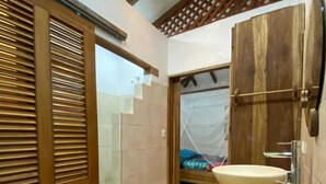 Een badkamer met een houten wastafel, een ruime wasbak en een douchehoek.