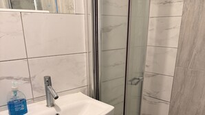 Une salle de bain avec un lavabo blanc, un miroir et une cabine de douche en verre.