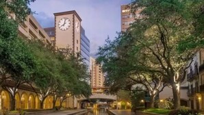 A canal with buildings on either side, a clock tower, and trees.