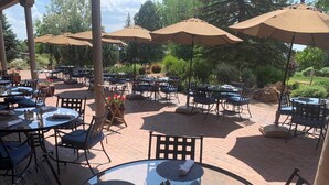An outdoor patio with round tables and chairs, surrounded by umbrellas and potted plants. - Quail Run 101 | Private Patio | Golf Course | Pool & Hot Tub | Tennis & Pickleball | Spa (Santa Fe)