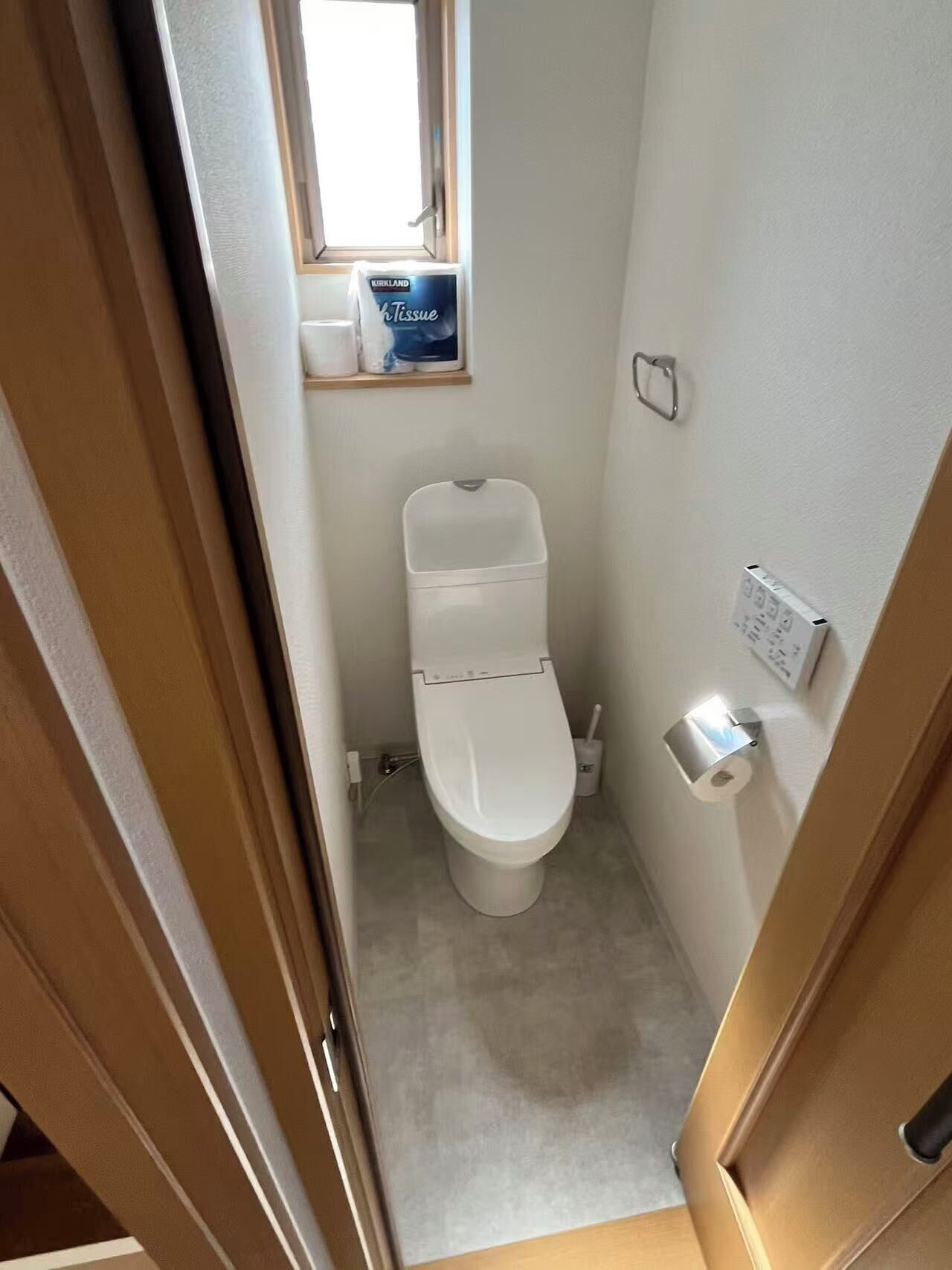 A small, clean bathroom with a toilet, a toilet paper holder, and a tissue box on the wall.