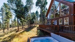 A wooden cabin with large windows, a deck, and a hot tub. - Bearfoot Lodge in Angel Fire (Angel Fire)