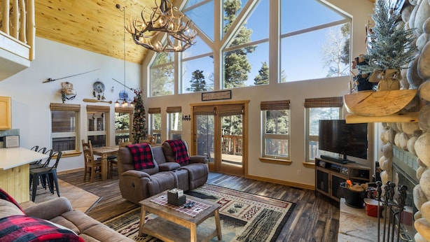 A spacious living room with a large window, a fireplace, and a cozy seating area. - Bearfoot Lodge in Angel Fire (Angel Fire)