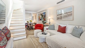 Una sala de estar moderna con una escalera, un comedor y un conjunto de sofás.