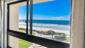 A window with a view of a beach and ocean. - Beach View Condo in the heart of Pacific Beach! (San Diego)