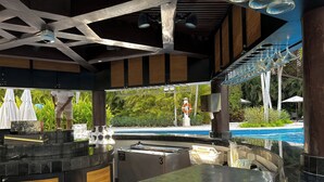 Ein Barbereich am Pool mit Pool, Sonnenschirmen und einem Rettungsring.