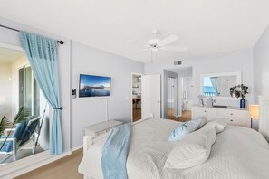 A bedroom with a bed, a ceiling fan, a TV, a desk, and a chair. - Luxurious Penthouse W/ Direct Ocean Front  Balcony, Heated Pool & Hot Tub!  🌊 (Cape Canaveral)