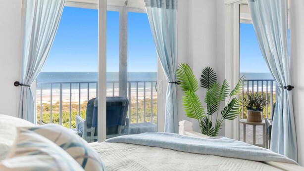 A bedroom with a view of the beach, a bed, a chair, and a potted plant. - Luxurious Penthouse W/ Direct Ocean Front  Balcony, Heated Pool & Hot Tub!  🌊 (Cape Canaveral)