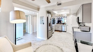 Una cocina moderna con una isla central, electrodomésticos de acero inoxidable e iluminación colgante.