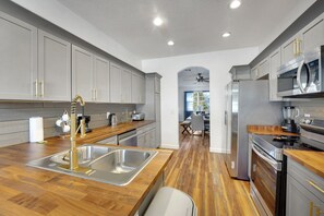 Una cocina moderna con armarios grises, electrodomésticos de acero inoxidable y encimera de madera.