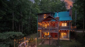Eine zweistöckige Blockhütte mit Balkon, umgeben von einem Wald.