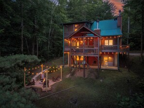 Eine zweistöckige Blockhütte mit Balkon, umgeben von einem Wald.
