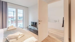 Een moderne slaapkamer met een bed, een televisie en een badkamer zichtbaar door een open deur.