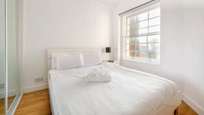 Ein Schlafzimmer mit einem großen Bett, einem Fenster und Blick auf die Stadt.