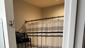 A small bathroom with a toilet, a shelf with toiletries, and a striped shower curtain.