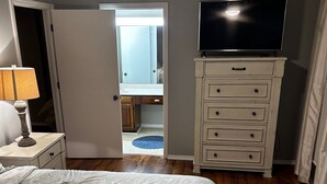 A bedroom with a bed, a dresser, a television, and a ceiling fan.