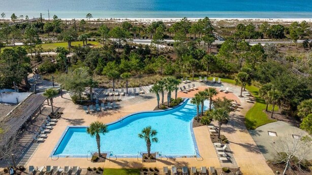 Ett semesterhotell med en stor pool, solstolar och utsikt över stranden.