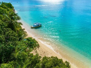 Una platja d'aigua turquesa cristal·lina, un vaixell i vegetació tropical exuberanta.