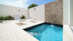 A swimming pool with two lounge chairs and a stone wall. - NEW villa with plunge pool, 3 mins to beach - Sorrento 10 (2 bed) (Lower Carlton)