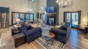 A spacious living room with a fireplace, modern furniture, and large windows offering a view of the outdoors. - Luxury + Close to slopes + Golf Side (McHenry)