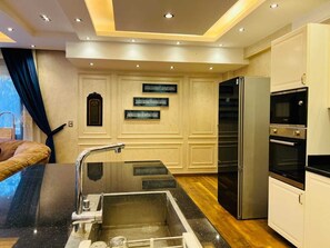 A modern kitchen with a built-in sink, stainless steel appliances, and decorative wall art. - Alsawah 3BR Duplex with garden in Eastown sodic (New Cairo)