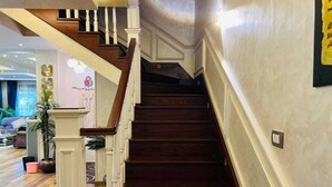 A wooden staircase with white balusters leading to an upper floor. - Alsawah 3BR Duplex with garden in Eastown sodic (New Cairo)