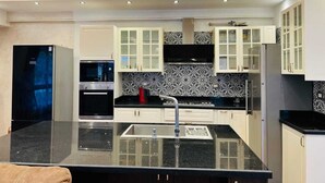 A modern kitchen with white cabinets, black countertops, and a black backsplash. - Alsawah 3BR Duplex with garden in Eastown sodic (New Cairo)