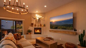 Una sala acogedora con chimenea, un cuadro de paisaje grande y una lámpara moderna.