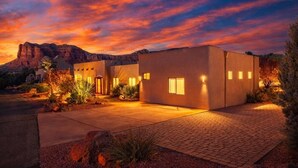 Una casa moderna con entrada pavimentada e iluminación exterior al caer la noche.